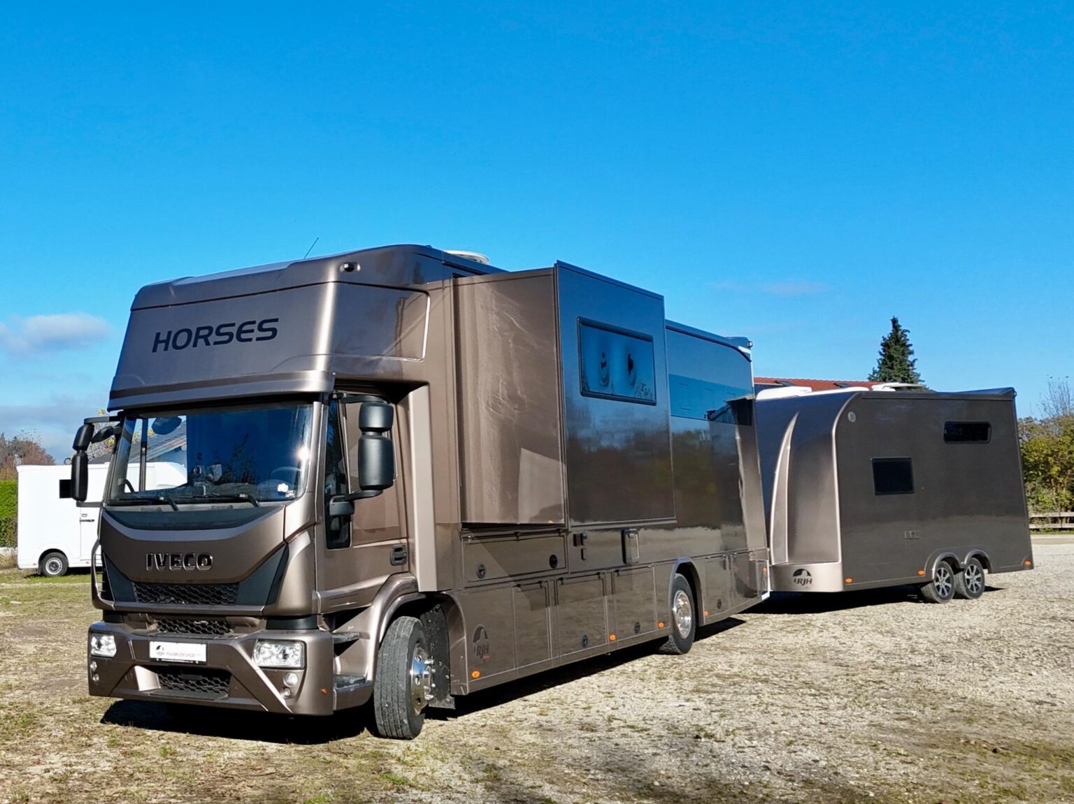 Seitenansicht eines braunen IVECO Pferdetransporters mit Pferdeanhänger unter blauem Himmel