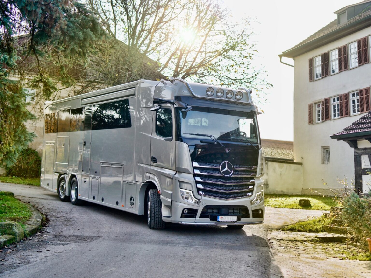 Luxus Pferdetransporter fährt um die Kurve neben einem Haus.