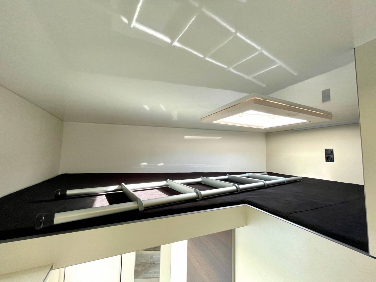 Geräumiger Schlafplatz mit Dachfenster und Leiter über dem Bad im Pferdetransporter